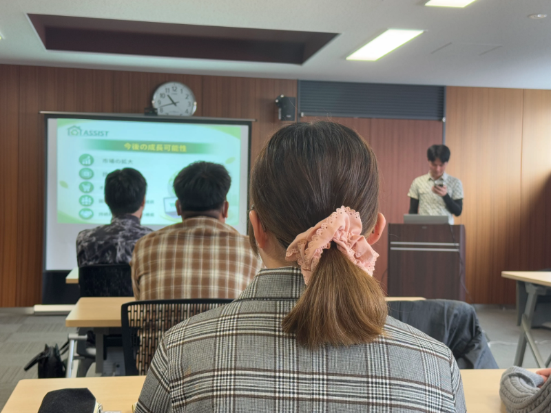 プレゼンをする新入社員と、仲間の発表に耳を傾ける新入社員